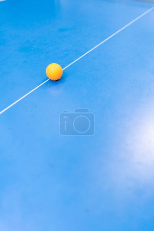 Foto de Una pelota de tenis naranja descansa sobre una mesa de tenis azul junto a una red en un parque de la ciudad el concepto de jugar ping pong al aire libre - Imagen libre de derechos