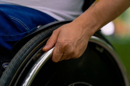 Photo for Inclusiveness Close-up of the hand of a man with disabilities who rides a wheelchair in city park - Royalty Free Image