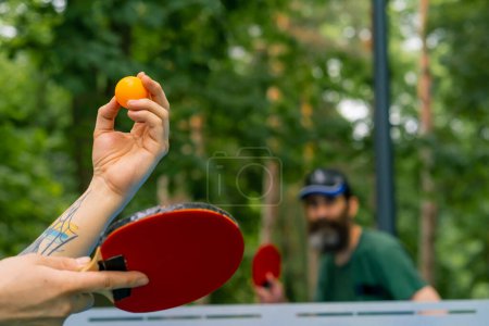 Photo for A close-up of a ping-pong ball being served against the background of an older man with gray beard who is preparing to kick the ball - Royalty Free Image