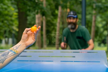 Photo for A close-up of a ping-pong ball being served against the background of an older man with gray beard who is preparing to kick the ball - Royalty Free Image