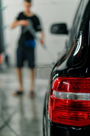Téléchargez les photos : Gros plan du feu arrière d'une voiture noire de luxe après le nettoyage à sec et les détails au lavage de la voiture - en image libre de droit