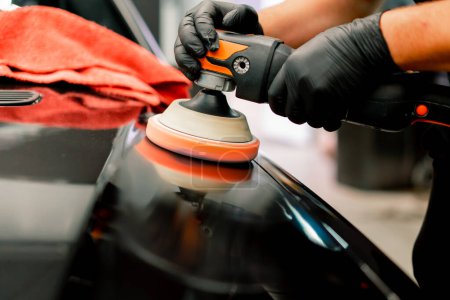 Photo for Close-up of a car wash worker using a polishing machine to polish the hood of  black luxury car - Royalty Free Image
