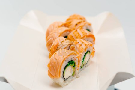 Téléchargez les photos : Gros plan d'un rouleau de phillXoa avec concombre de saumon et fromage cottage sur fond blanc dans une boîte à sushi - en image libre de droit