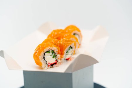 Foto de Primer plano de un rollo de filigrana con pepino de salmón y requesón sobre un fondo blanco en una caja de sushi - Imagen libre de derechos