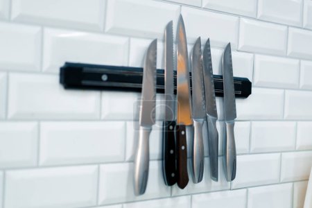 Foto de Un primer plano de un conjunto de cuchillos colgando en la pared en la cocina profesional del restaurante de sushi - Imagen libre de derechos
