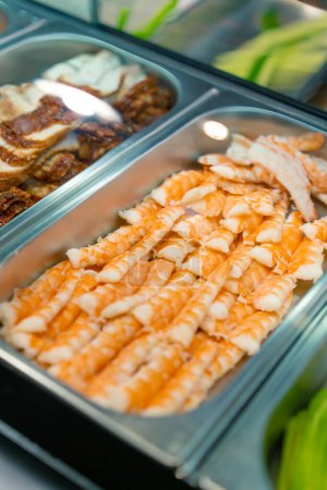 Téléchargez les photos : Gros plan sur les ingrédients du sushi dans des plateaux métalliques professionnels crevettes saumon anguille crevettes avocat dans la cuisine du restaurant de sushi - en image libre de droit