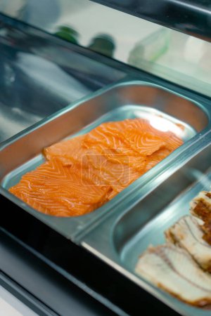 Foto de Primer plano de ingredientes de sushi en bandejas profesionales de metal salmón camarones anguila camarones aguacate en la cocina del restaurante de sushi - Imagen libre de derechos