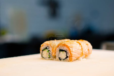 Photo for Close-up of philadelphia roll with seared salmon cream cheese and cucumber on white kitchen board in the background of the kitchen - Royalty Free Image