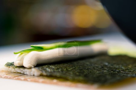Téléchargez les photos : Close-up du procédé de fabrication des rouleaux de riz au concombre nori fromage à la crème et saumon - en image libre de droit