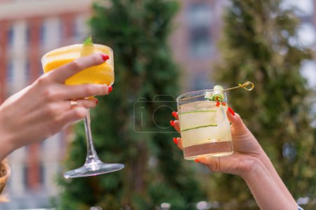 Foto de Primer plano de amigos brindando con cócteles en la terraza de verano en el bar del club - Imagen libre de derechos