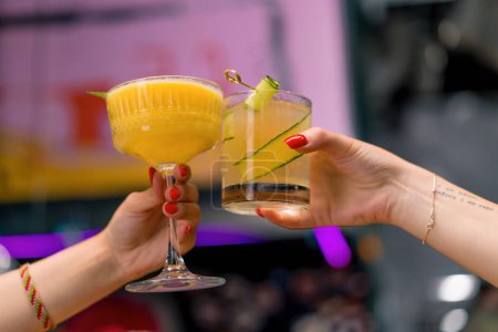 Photo for Close up of two people cheering cocktails in bar or disco club drinks and cocktails concept - Royalty Free Image