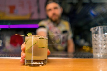 Foto de Un joven camarero profesional ofrece un delicioso cóctel alcohólico al cliente en el club del bar - Imagen libre de derechos