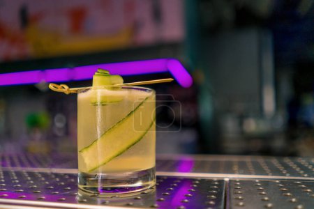 Téléchargez les photos : Fraîchement préparé gin garden cocktail alcoolisé avec trancheuse de concombre se trouve sur le comptoir du bar dans le bar club - en image libre de droit