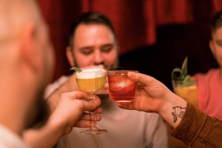 Téléchargez les photos : Un groupe d'amis dans un bar boire des cocktails et s'amuser Toasting cocktails Lunettes dans le club bar close-up - en image libre de droit