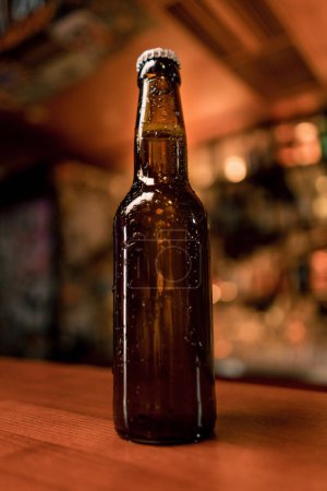 Foto de Primer plano de una botella cerrada de cerveza con etiquetas en un mostrador de bar en el bar del club - Imagen libre de derechos