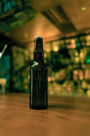 Foto de Primer plano de una botella cerrada de cerveza con etiquetas en un mostrador de bar en el bar del club - Imagen libre de derechos