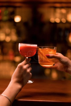 Téléchargez les photos : Proche de deux personnes acclamant des cocktails dans un bar ou un club discothèque concept boissons et cocktails - en image libre de droit