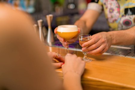 Foto de Un joven camarero profesional le da un delicioso cóctel alcohólico a una chica cliente en un club en el bar - Imagen libre de derechos