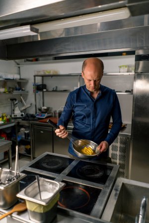 Foto de Un chef en una cocina profesional bate los ingredientes con batidor para hacer helado de autor artesanal - Imagen libre de derechos