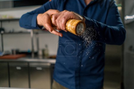 Photo for Close-up of a chef holding pepper and salt grinder in his hands grains of spices fall in the air - Royalty Free Image