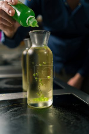 Foto de Un chef en experimentos profesionales de cocina añadiendo granos de caviar molecular multicolor a un recipiente con agua de cerca - Imagen libre de derechos