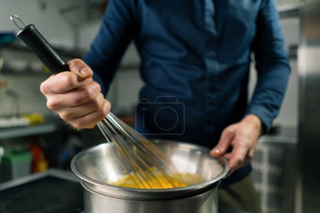 Photo for A chef in a professional kitchen whips the ingredients with whisk for making craft author's ice cream close-up - Royalty Free Image