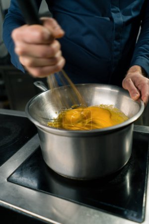 Téléchargez les photos : Un chef dans une cuisine professionnelle fouette les ingrédients avec du fouet pour faire de la crème glacée artisanale close-up - en image libre de droit