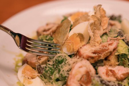 Photo for Close-up of a white plate with Caesar salad with chicken and egg on a table in a club bar - Royalty Free Image