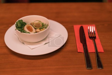 Photo for Close-up of a white plate of chicken broth with egg and herbs on a table in club bar - Royalty Free Image