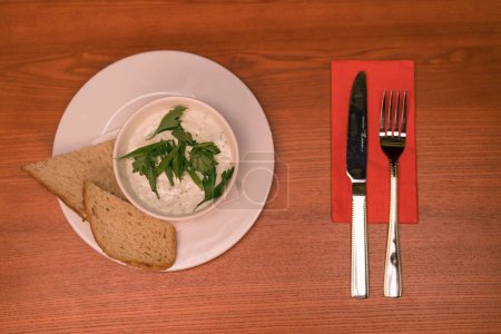 Foto de Primer plano de un plato blanco con salsa blanca y verduras y crutones de pan en una mesa en el bar del club - Imagen libre de derechos