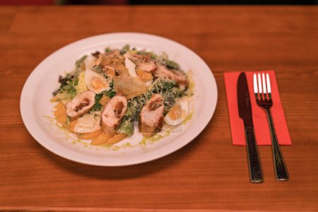 Photo for Close-up of a white plate with Caesar salad with chicken and egg on a table in a club bar - Royalty Free Image