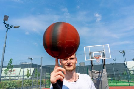 Foto de Primer plano del jugador de baloncesto chico haciendo girar una pelota de baloncesto en su dedo mostrando sus habilidades de baloncesto estilo libre - Imagen libre de derechos