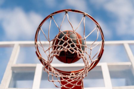 Téléchargez les photos : Un gros plan de basket-ball cerceau dans lequel un basket-ball frappe le concept de l'admiration pour le jeu de basket-ball et l'amour de travailler - en image libre de droit