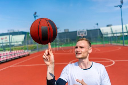 Téléchargez les photos : Gros plan d'un joueur de basket-ball filant un ballon de basket-ball sur son doigt montrant ses compétences en style libre de basket-ball - en image libre de droit