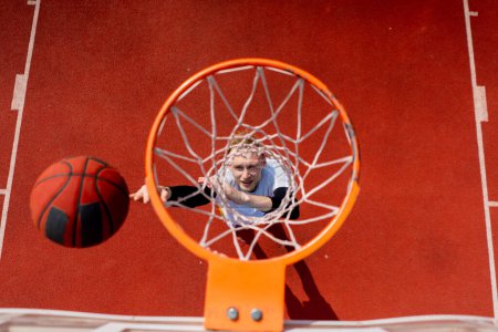 Photo for Close-up of basketball ring into which a tall guy basketball player throws the ball from below the concept of admiring the game of basketball - Royalty Free Image