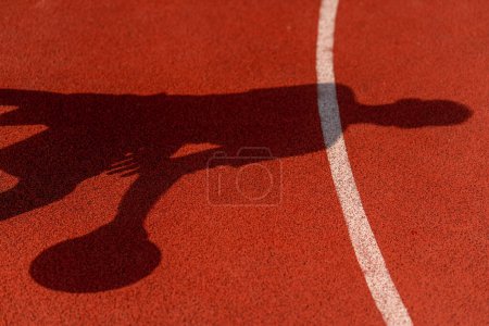 Photo for Close-up of basketball guy's shadow on the floor of a basketball court while dribbling the ball - Royalty Free Image