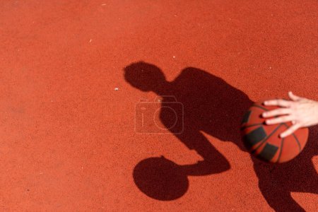 Photo for Close-up of basketball guy's shadow on the floor of a basketball court while dribbling the ball - Royalty Free Image