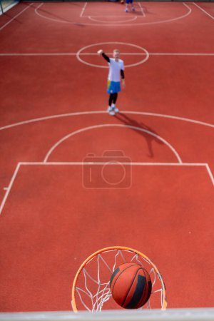 Téléchargez les photos : Gros plan de l'anneau de basket dans lequel un grand joueur de basket-ball lance la balle Le concept d'admirer le jeu de basket-ball - en image libre de droit