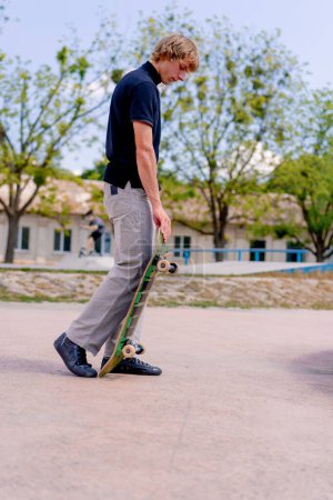 Foto de Un joven patinador se para en un skatepark con un monopatín en la mano antes de empezar a patinar - Imagen libre de derechos