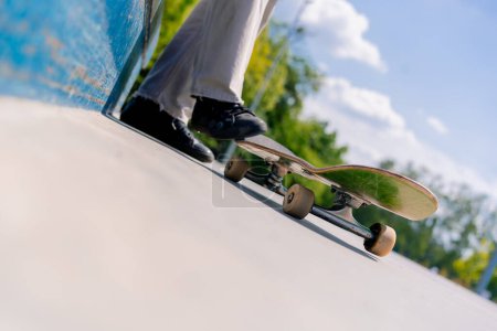 Téléchargez les photos : Gros plan des jambes d'un skateboarder avec une planche à roulettes tout en se reposant entre les tours au skatepark de la ville - en image libre de droit