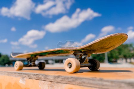 Téléchargez les photos : Un gros plan d'une planche à roulettes qui se tient sur un banc dans un skatepark de la ville le concept de l'adrénaline envie et l'amour pour le skateboard - en image libre de droit