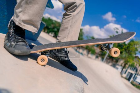 Photo for Close-up of a skateboard being held by the foot of a young skateboarder in city skatepark - Royalty Free Image