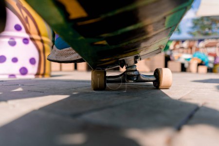 Téléchargez les photos : Gros plan de la planche à roulettes qui roule sur un sentier dans un parc public vue d'en bas le concept de l'adrénaline envie et l'amour pour le skateboard - en image libre de droit