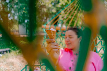 Téléchargez les photos : Jeune fille couchée sur un hamac dans le parc se reposant de roller et manger de la crème glacée - en image libre de droit