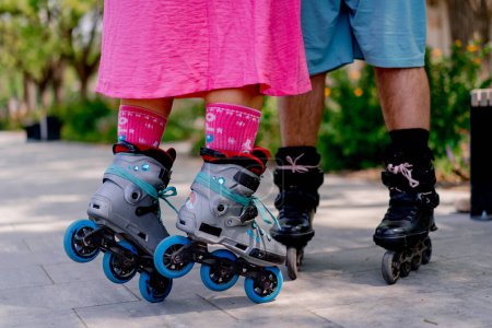 Photo for Close-up of the legs of a couple man and woman rollerblading in the park while on date - Royalty Free Image