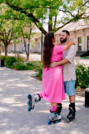 Téléchargez les photos : Jeune couple sur rollerblades mec et fille câlin pendant la date dans le parc plus les modèles de taille - en image libre de droit