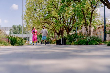 Téléchargez les photos : Jeune couple mec et fille roller en été dans le parc de la ville tout en datant modèles plus la taille - en image libre de droit