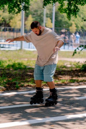 Foto de Joven con barba aprende a patinar en un parque de la ciudad concepto de querer aprender cosas nuevas y positividad corporal - Imagen libre de derechos
