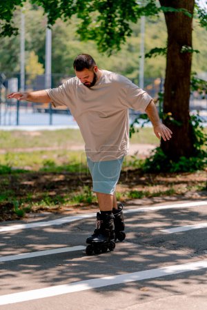 Foto de Joven con barba aprende a patinar en un parque de la ciudad concepto de querer aprender cosas nuevas y positividad corporal - Imagen libre de derechos