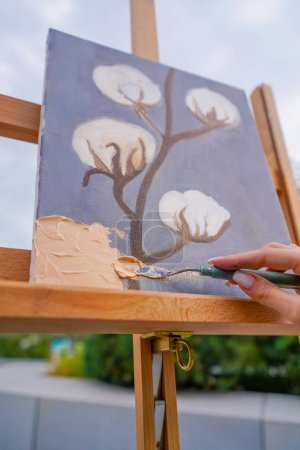Téléchargez les photos : Gros plan d'une fille artiste appliquant de la peinture à l'huile avec une spatule à une peinture en cours de création - en image libre de droit